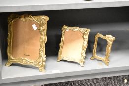 A group of three graduating cast-brass Art Nouveau style photograph frames, the largest measuring