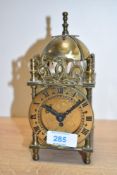 A Smiths brass mechanical lantern clock, having a domed bell top with engraved circular dial and