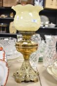 A 19th / early 20th century oil lamp having floral milk glass shade and twin wick winders, raised on
