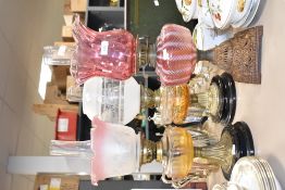 A 19th century oil lamp having flared cranberry glass shade and two level burners, raised on a