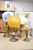 An early 20th century brass oil lamp having floral glass shade, glass chimney and raised on a