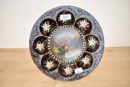 A 19th century Hubert Sattler pottery charger, the centre hand painted depicting a Swiss landscape