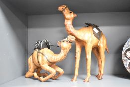 A pair of Liberty of London style Camel sculptures, having original saddles, glass eyes and aged