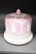 A late 19th century / early 20th century pink Jasperware cheese dome, having acorn finial, decorated