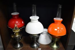 A vintage Aladdin paraffin lamp having an orange glass shade and clear glass chimney, h61cm, sold