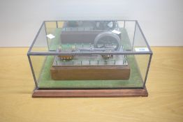 A Live Steam model of a horizontal Engine surrounded by a wooden block with wooden plinth with