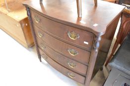 A reproduction bow front chest of four drawers, having column supports