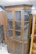 An early to mid 20th Century oak display cabinet having canted design with double cupboard under,