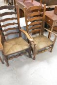 Two traditional oak ladder back carver chairs having rush seats