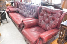A modern burgundy leather button back three piece suite