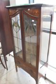 An Art Nouveau mahogany display cabinet, having typical inlaid decoration and leaded glass doors,