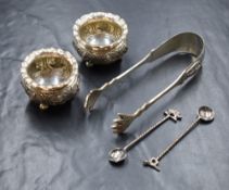 A pair of Eastern white metal salts, of bulbous form having crimped rims with figures to the body,