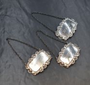 Three Elizabeth II silver decanter labels, of rectangular form having scroll and shell borders for