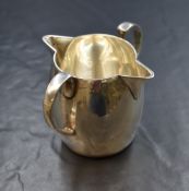 A George V silver milk jug, of cylindrical slightly bulbous form, having two C-curve handled and two