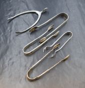 A group of five silver sugar tongs, one of wish bone form, one having claw hands, and one having