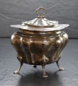 A George V silver tea caddy, of lobed oval form, having Chippendale style rim raised on four