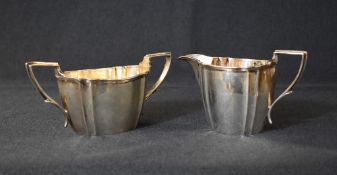 A George V silver sugar and cream, of oval form having canted ends and angular handles, marks for