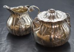A Japanese white metal sugar and cream, of squat bulbous form in a lilypad motif, having embossed