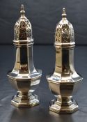 A pair of Edwardian silver casters, of bulbous octagonal form having a finial cover over pierced top