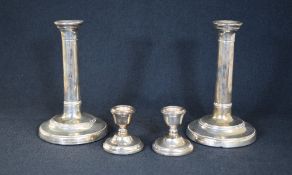 A pair of Edwardian silver candlesticks, having step moulding to the attached sconces and banding to