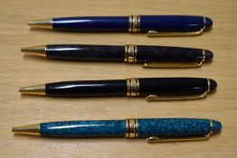 Four L'Plume ballpoint pens one blue, a grey, a black and turqoise with gold trim. The black is