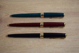 Three Parker 17 Super Duofold ballpoint pens in black, red, and green.