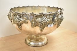 A silver plated punch bowl raised on a stout footed base, decorated with fruit and foliage, h25.5cm