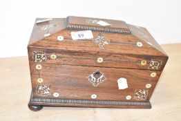 A 19th century rosewood tea caddy of sarcophagus form, supported on bun feet, decorated with pearl