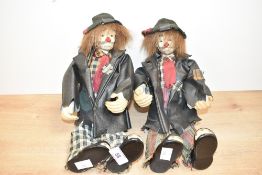 A pair of porcelain clown dolls wearing leather jackets and tartan shirts, h31cm