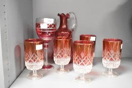 A cranberry glass water jug having swirl body, shaped spout and handle, h22.5cm, sold together