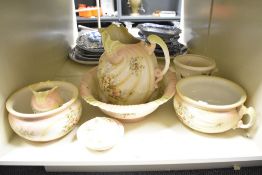 An early 20th century porcelain pitcher and wash basin, decorated with pink and green foliage on a