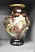 A Majolica style urn of lobed form having shaped spout, decorated with horned beasts, fish and