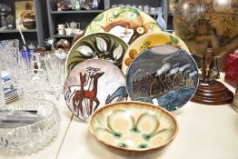 A large studio pottery charger, hand painted with floral patterns, signed C.Accaid bottom left,