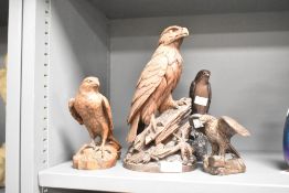 A Black Forest style wooden eagle sculpture having glass eyes and perched upon a rockfall, h25.