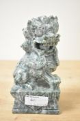 A Chinese carved green stone Dog of Foe, modelled with mouth gaping and front paw resting on a ball,