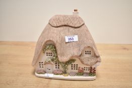 A ceramic country cottage table lamp, having thatched roof and pierced windows, L20cm