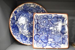 A large blue and white circular charger hand coloured with fruit and foliage, signed to back J. A.