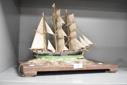 A 20th century ship model diorama, fully rigged, raised on a sea bed supported on a wooden base,