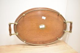 An oval oak serving tray having twin handle, gallery mounts and centre plaque, w46cm