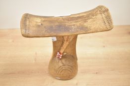 A tribal Ethiopian Gurage headrest having a curved top with carved geometrical patterns and bands of