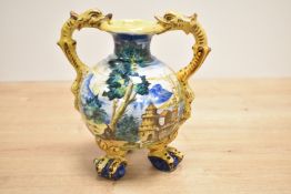 A Majolica style vase decorated with multiple colour glazes and fish form handles, supported on