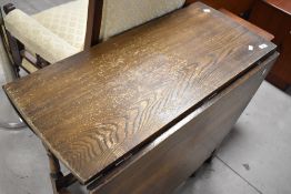 A traditional oak gateleg table , dark stained with significant wear