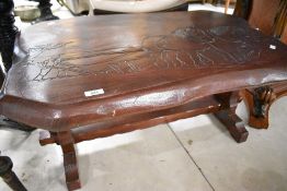 A rustic dark stained coffee table having carved plough themed decoration, approx. 87 x 54cm