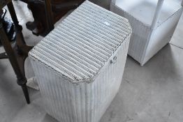 A Lloyd Loom linen basket and a similar bedside table