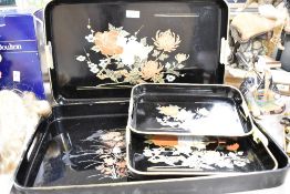 A three piece black lacquerware tray set sold along with another similar tray
