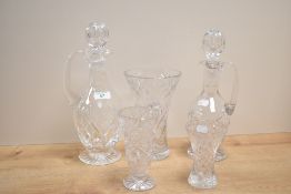 A small group of cut crystal glass comprising two decanters and three vases, one being footed.