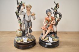 Two large vintage Capodimonte style figures depicting a male and female child amongst fruit trees,