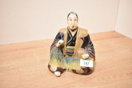 A Japanese stoneware figure of a seated man with a box by his side, h14cm Condition report: