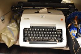A vintage Olympia typewriter with soft cover and spare ink ribbon