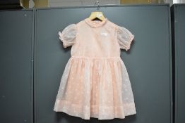 A 1950s early-years childrens dress in baby pink Bri-Nylon, comprising two dresses to be worn